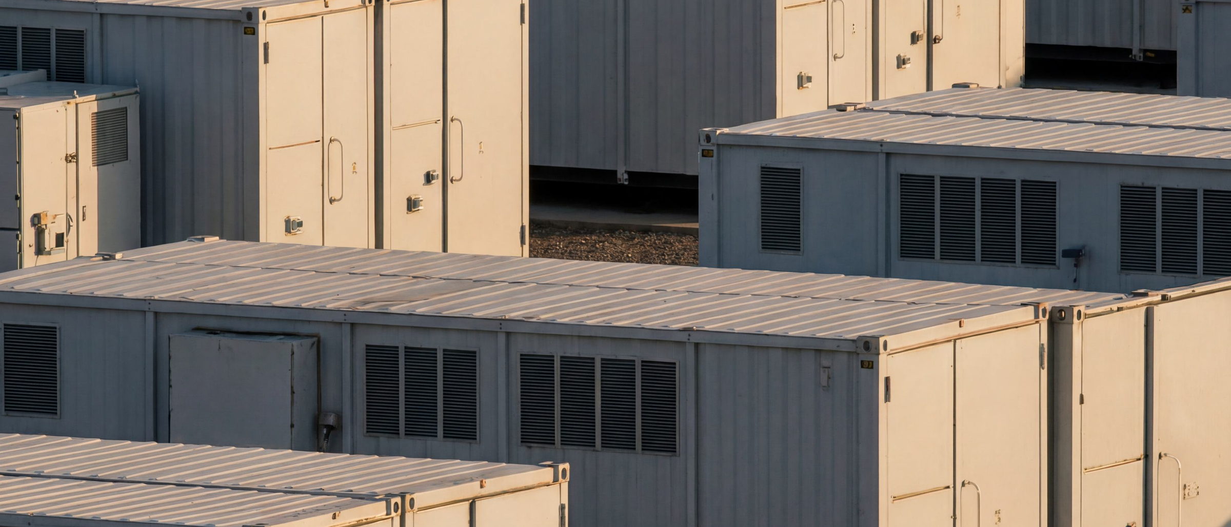 Rows of utility-scale battery storage enclosures at dusk
